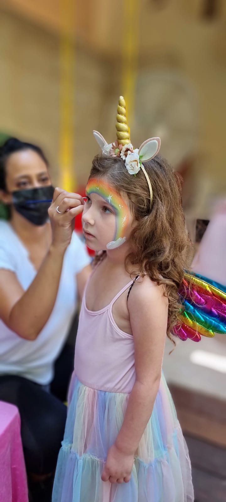 ילדה עם איפור פנים וכנפי פיה קסומות בקונספט חד-קרן ופיות של אבקת פיות